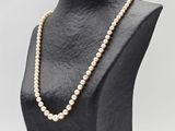 a white pearl necklace on a black mannequin