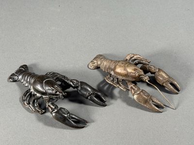 two metal lobsters sitting next to each other on a table