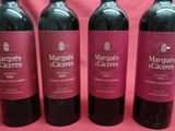 three bottles of red wine are lined up on a pink background