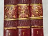 trois vieux livres sont alignés sur une surface blanche