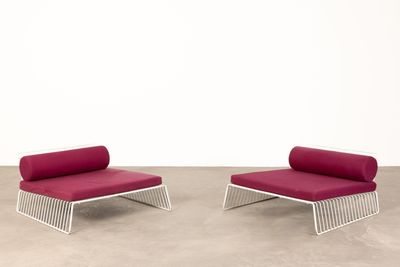une paire de chaises longues avec des coussins rouges dans une pièce blanche