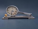 une horloge et une balle de tennis posées sur un socle en bois