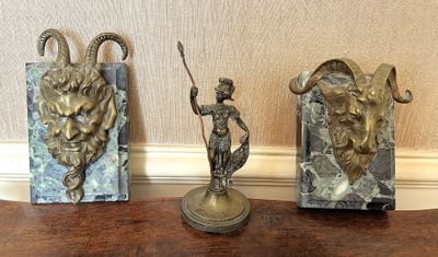 trois statues représentant un homme et une chèvre, posées sur une table
