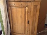 a wooden cabinet in the corner of a room with a vase on top of it