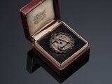 an image of a silver medal in a wooden box on a black surface