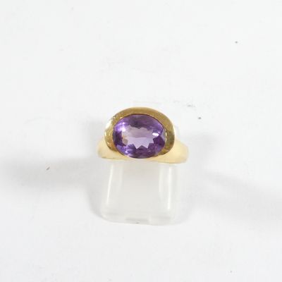 gros plan d'une bague en or avec une pierre violette
