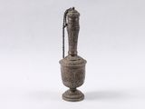 un vieux vase en métal dont le col est orné d'une chaîne