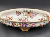 a close up of a bowl with flowers on it on a table