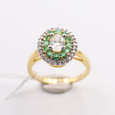 a close up of a diamond and emerald ring on a white surface