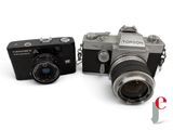 two cameras sitting next to each other on a white surface