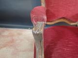 a red chair with a wooden arm rest and a glass vase on it
