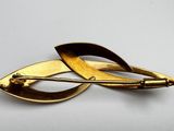 gold plated brooch with leaf design on a white background