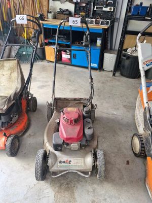 Trois tondeuses à gazon sont alignées dans un garage