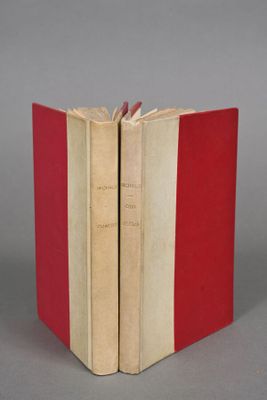 two red and white books sitting next to each other on a gray surface