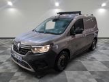 La camionnette grise est garée sur un sol carrelé à damier.