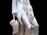 une statue blanche représentant une femme assise sur un banc
