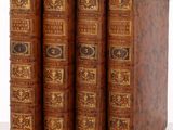 trois vieux livres posés l'un sur l'autre sur une surface blanche