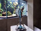 a statue of a fish on a pedestal in front of a fish tank
