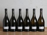six bottles of wine are lined up in a row on a wooden table