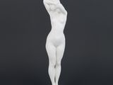 a white statue of a woman standing on a black surface