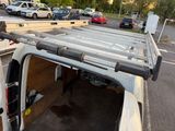 vehicles parked in a parking lot with a ladder on the back of a van