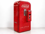 un distributeur de Coca-Cola rouge posé par terre