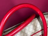 a red handle on a white purse against a pink background