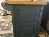 a black kitchen island with a wooden top in the middle of a tiled floor