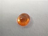 a close up of an orange sapphire stone on a white surface