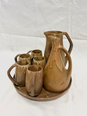 four cups and a pitcher on a tray on a table