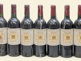 six bottles of wine lined up in a row on a white surface
