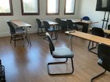 des tables et des chaises dans une salle de classe, avec un téléviseur à écran plat accroché au mur
