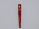 a red pen that is laying on a white surface