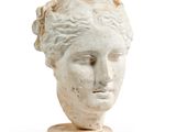 tête de femme en marbre posée sur un socle, sur fond blanc
