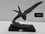 statue of a flying bird on a black base on a white surface