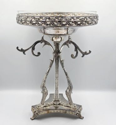 un plateau ancien en argent posé sur un support et recouvert d'un couvercle en verre