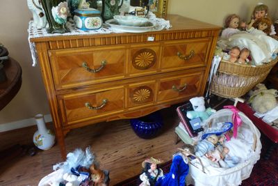 une commode sur laquelle se trouve un panier rempli de poupées