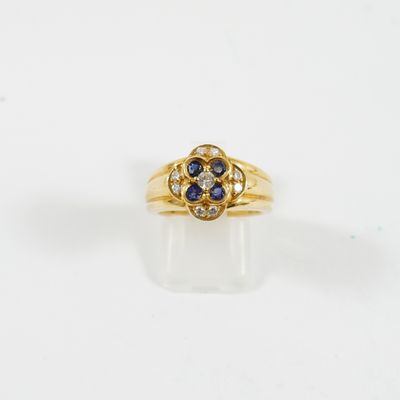 gros plan d'une bague en or avec des pierres bleues et blanches