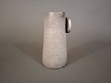 a white pitcher sitting on a table with a gray background