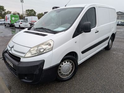 La camionnette blanche est garée sur le parking sous la pluie.