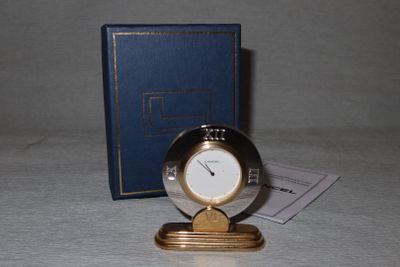 une petite horloge posée sur une table à côté d'un livre