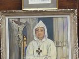 un tableau représentant une religieuse tenant une croix devant un portrait