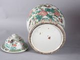 a vase with a lid sitting next to a small cup
