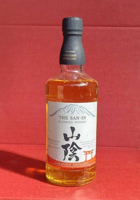 une photo d'une bouteille de whisky posée sur une table rouge