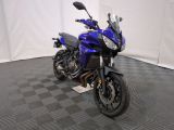 une photo d'une moto bleue garée sur un sol à damier