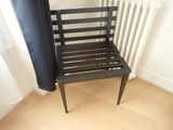 a black chair sitting next to a radiator in a room