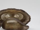 a silver bowl with a spoon in it on a white surface