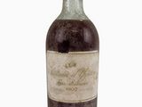 une vieille bouteille de vin posée sur une surface blanche