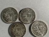 four silver coins sitting on top of each other on a white surface