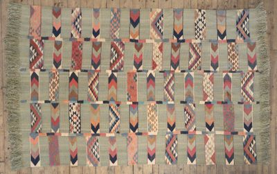 a large multicolored kilimi rug on a wooden floor